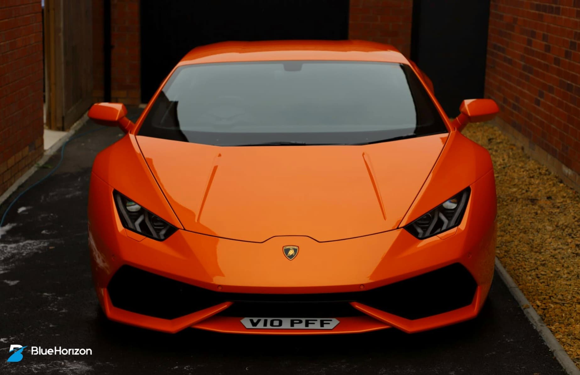 Front-on view of orange Lamborghini Huracan in driveway entrance after full professional detail