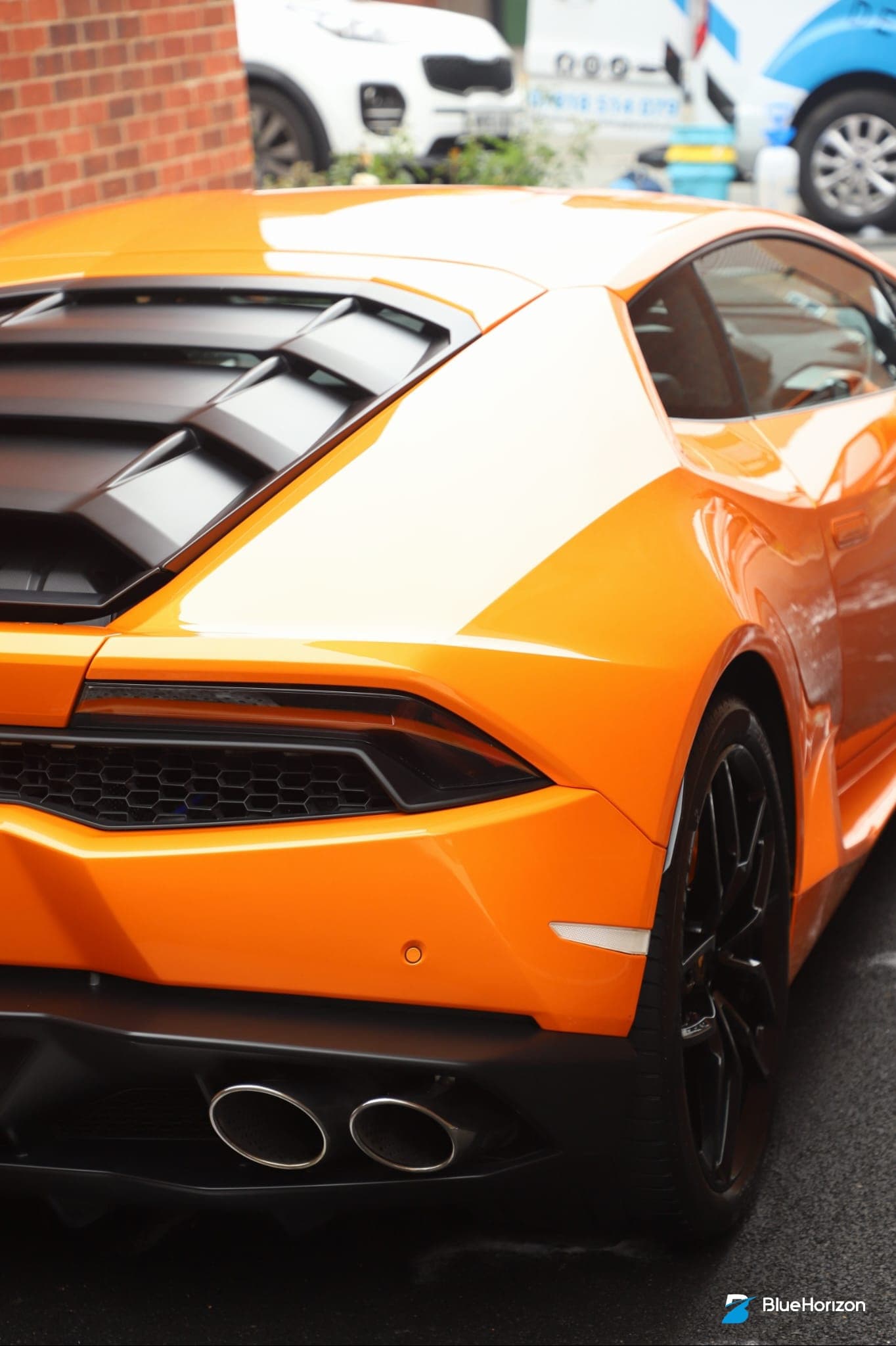 Rear quarter of orange Lamborghini Huracan showing engine intake vents and exhaust tips