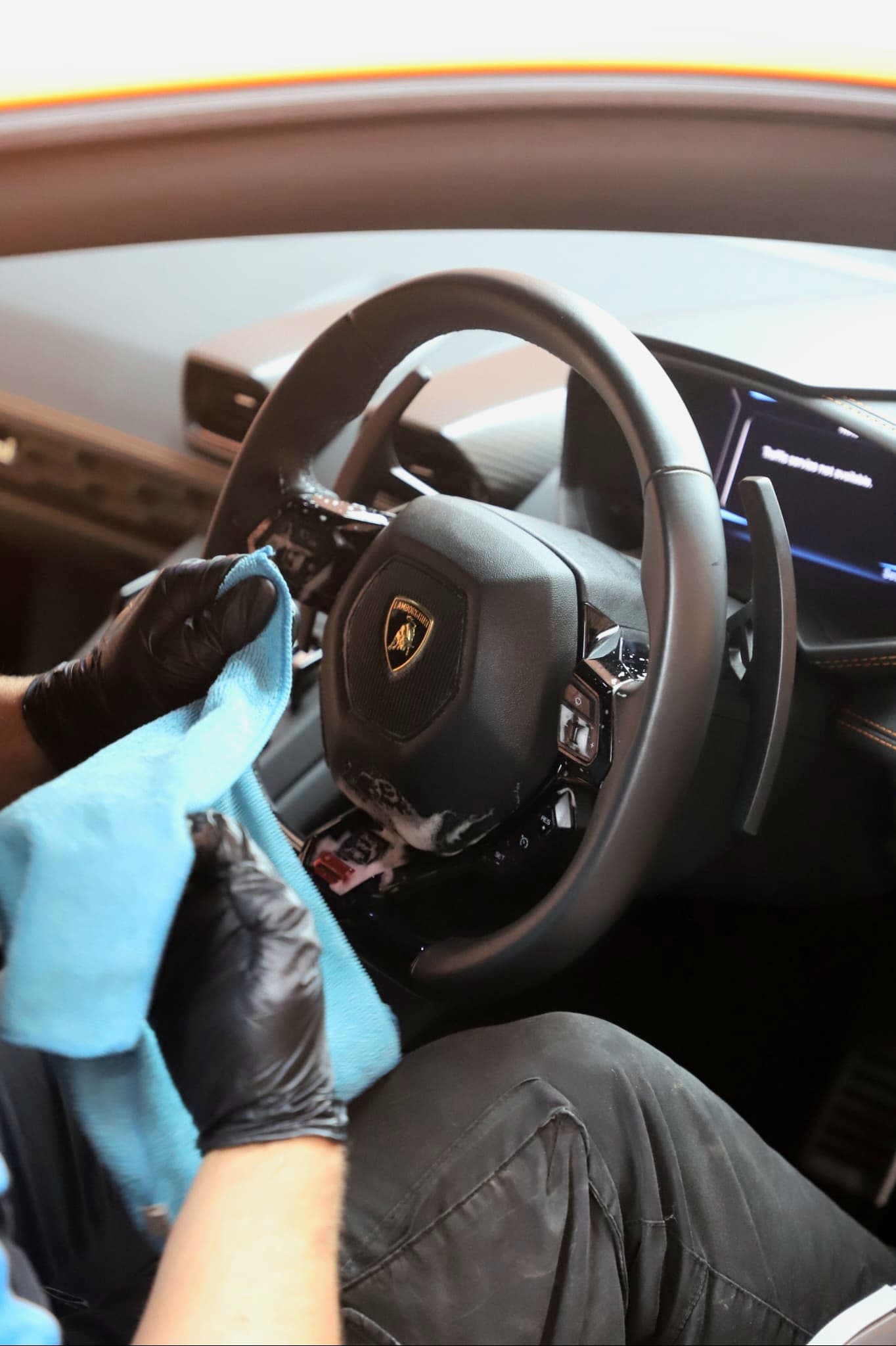 Final wipe of Lamborghini Huracan steering wheel with blue microfibre — perfect clean interior