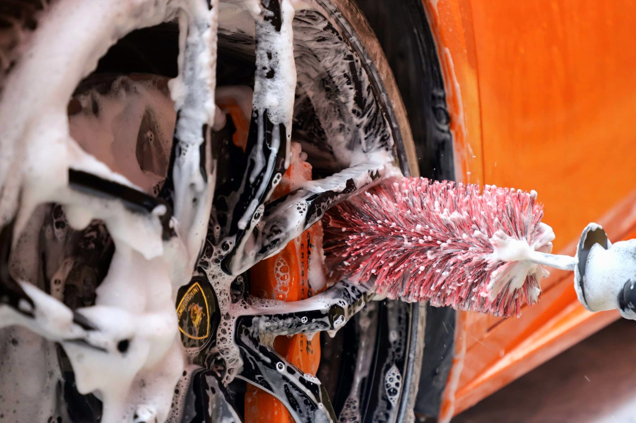 Specialist wheel brush cleaning foam-covered Lamborghini alloy wheel — wheel detail in Warwickshire