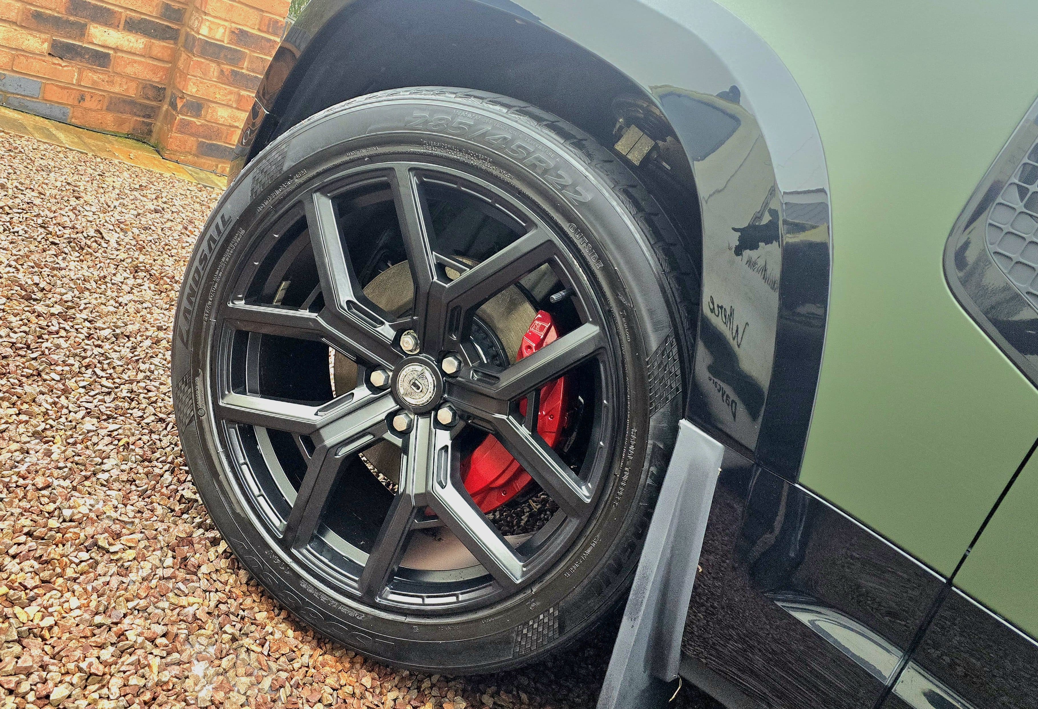 Dark alloy wheel with red brake caliper on Lamborghini Urus after refurbishment and caliper painting by Blue Horizon Detailing, Warwickshire