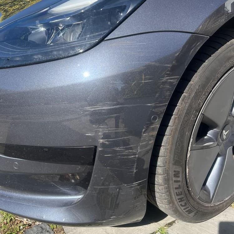 Close-up of bumper scuff and scratch damage on a Tesla Model 3 — the type of damage Blue Horizon SMART repairs can fix to factory standard