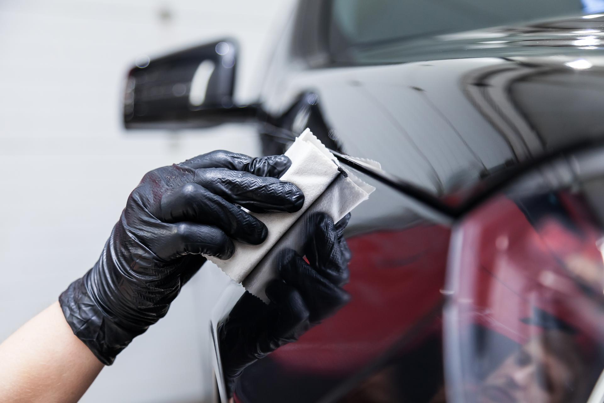 The process of applying a nano-ceramic coating on the car's fender by a male worker with a sponge and special chemical composition to protect the paint on the body from scratches, chips and damage.