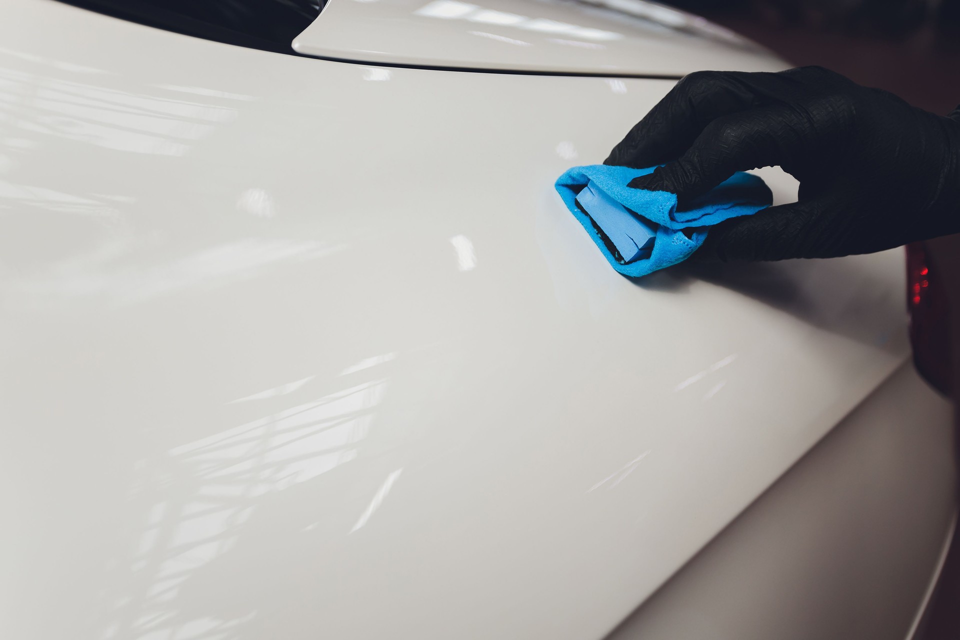 Car detailing - Man applies nano protective coating to the car. Selective focus.
