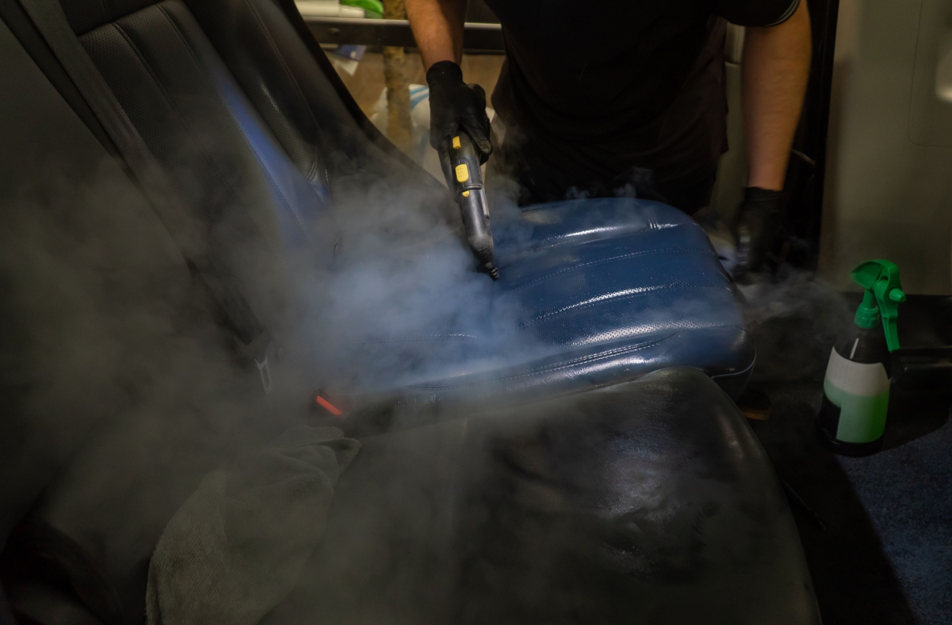 The detailing master cleans the car interior with a hot steam cleaner close-up. Dry cleaning of the car interior, close-up, selective focus.
