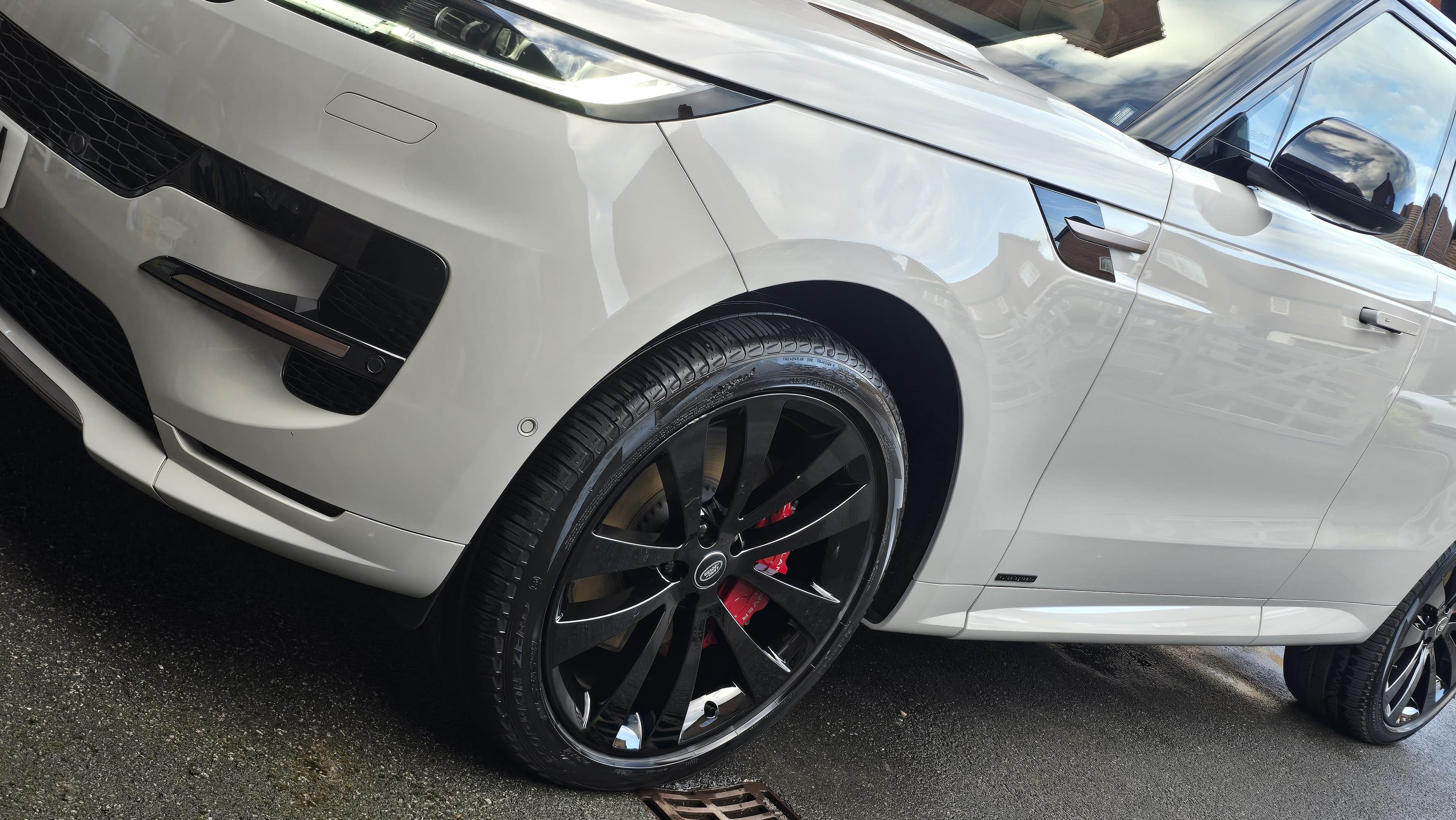 White Range Rover Sport showing deep paint gloss and black alloys with red calipers after ceramic coating protection by Blue Horizon Detailing, Warwickshire