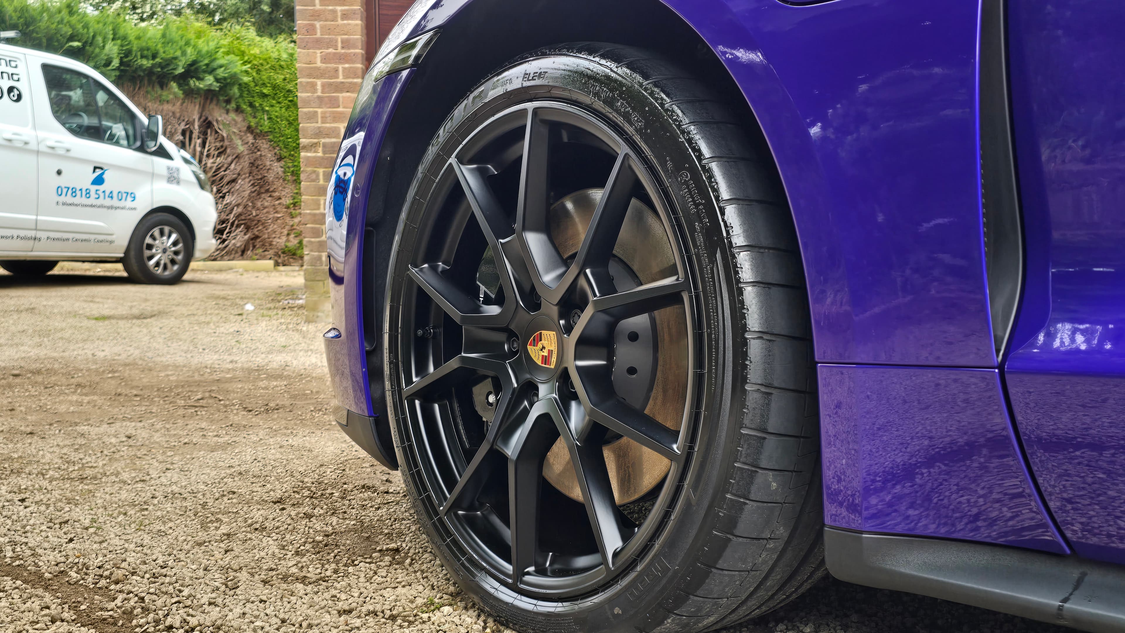 Porsche Taycan GTS black alloy wheel close-up with Blue Horizon Detailing van on-site — mobile ceramic coating Warwickshire