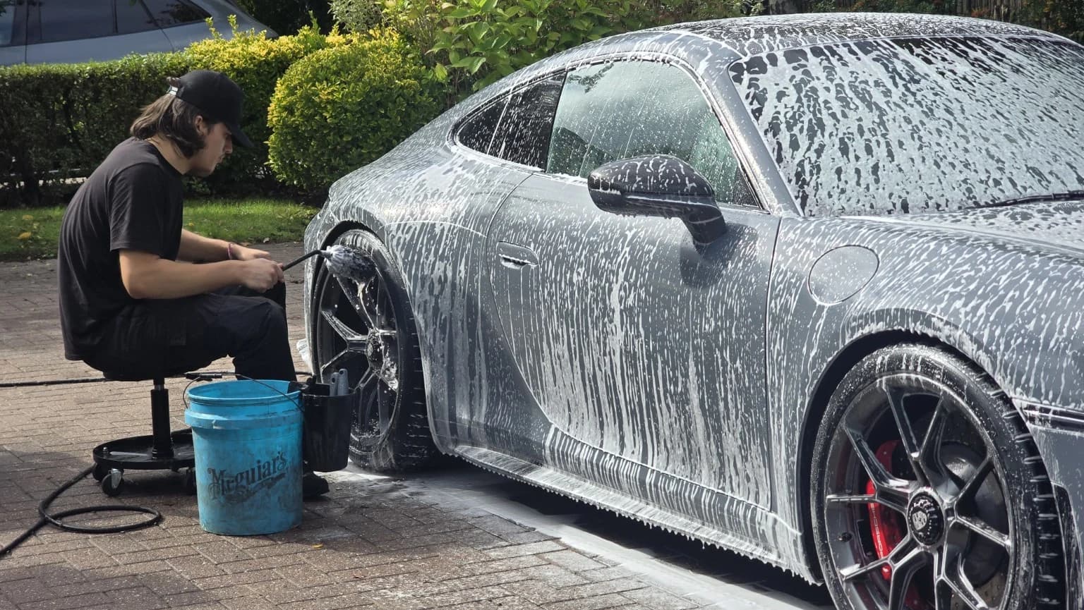 Careful wheel brushing on a foam-covered Porsche