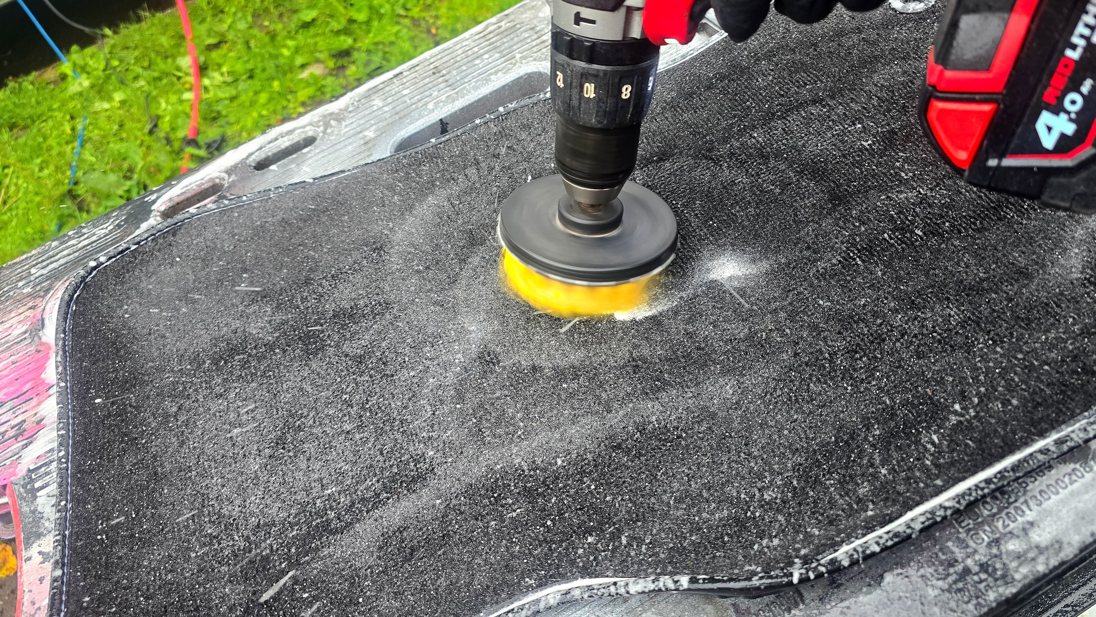 Sandy Jaguar F-Pace floor mat being deep cleaned with a drill brush and shampoo