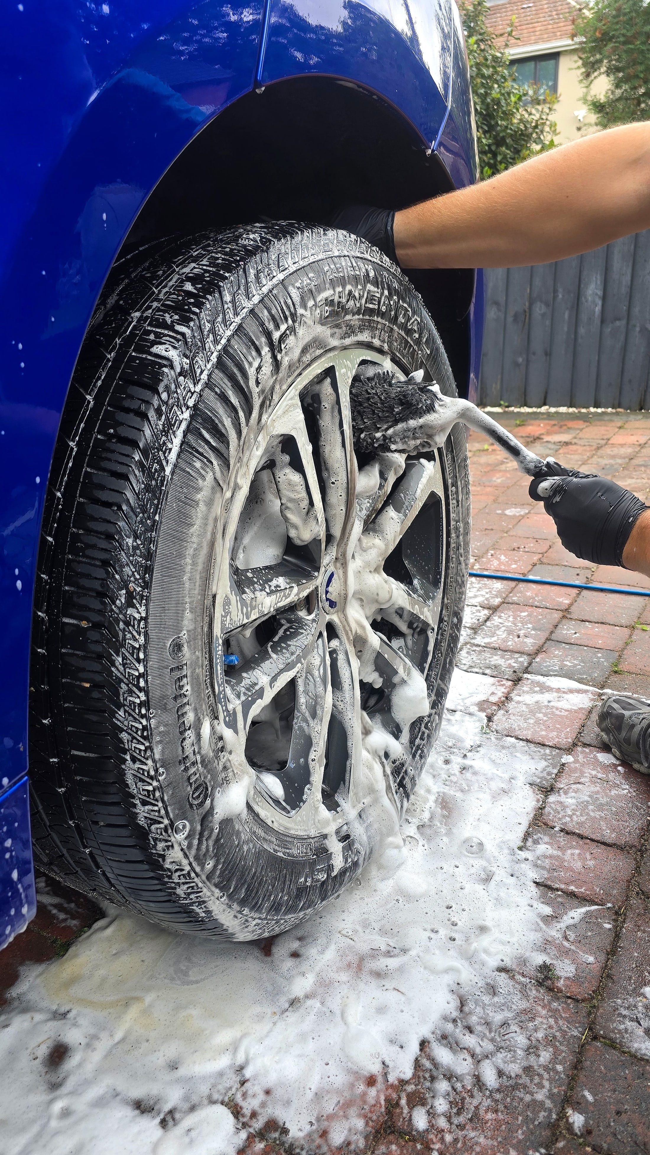 Jaguar F-Pace alloy wheel being deep cleaned with snow foam and a detailing brush